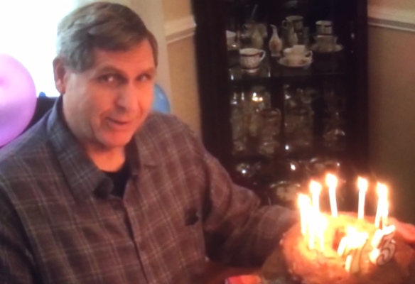 Cliff and birthday cake ablaze with candles